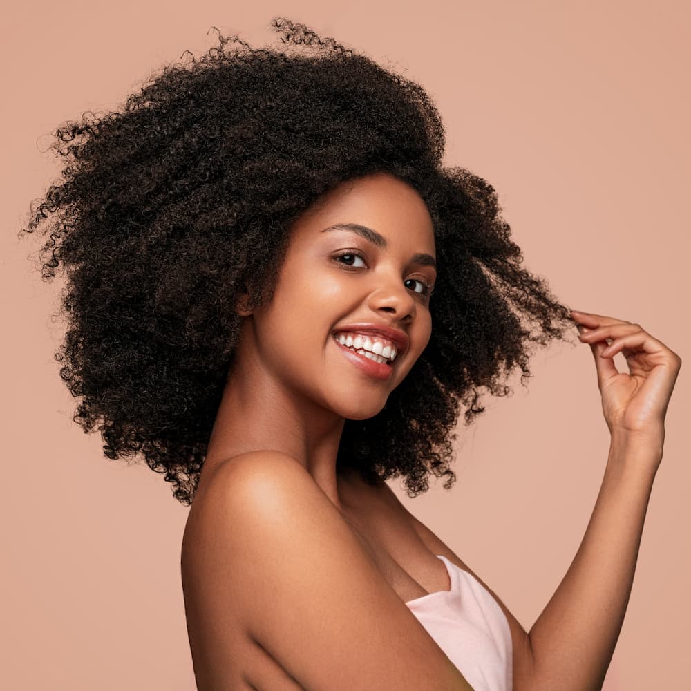 a happy woman posing while holding a piece of her hair