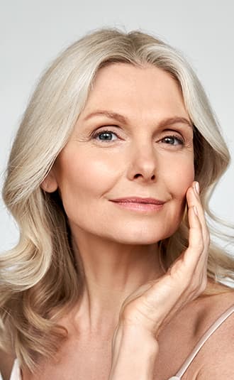 an older woman touching her cheek and smiling gently